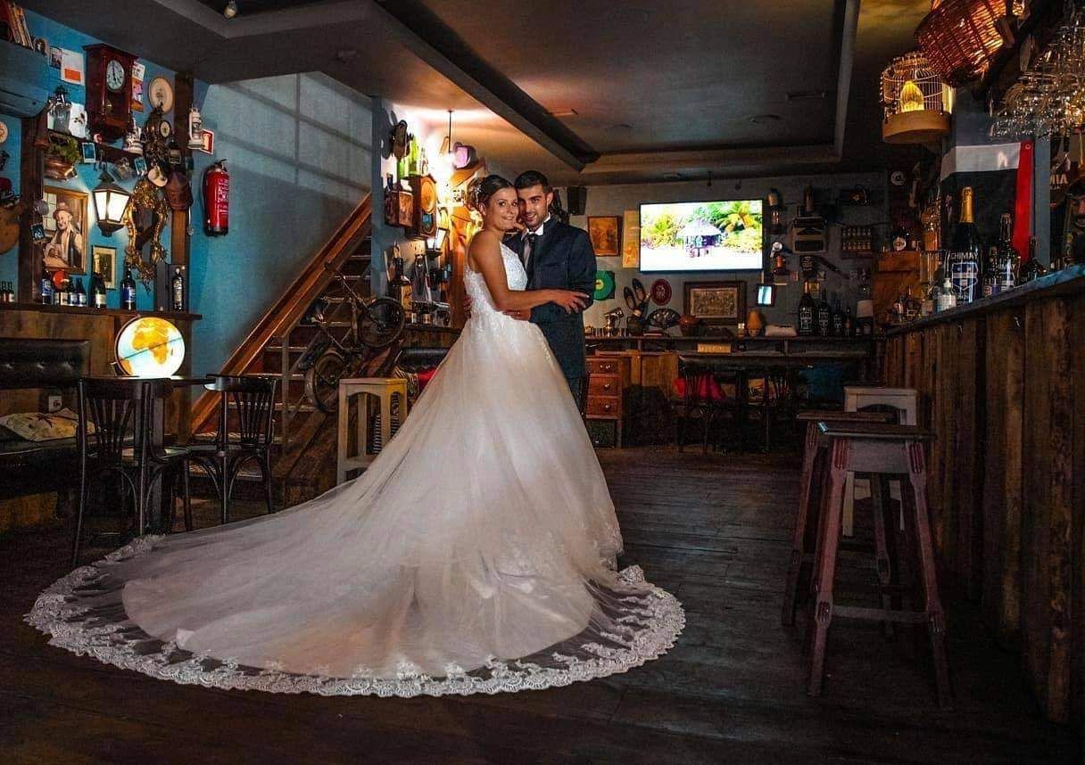 Une mariée et un marié posent pour une photo dans un restaurant. la mariée porte une longue robe de mariée.