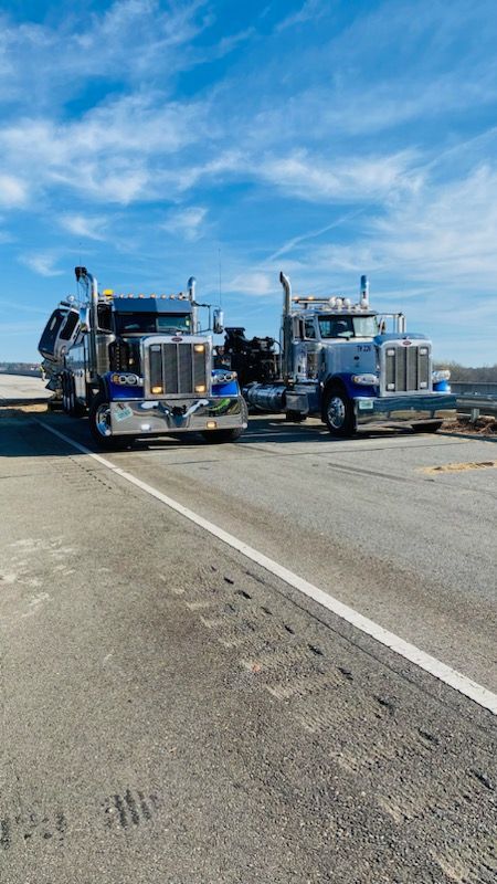 Two semi trucks are parked next to each other on the side of the road.