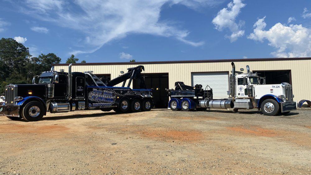Two tow trucks are parked in front of a building.
