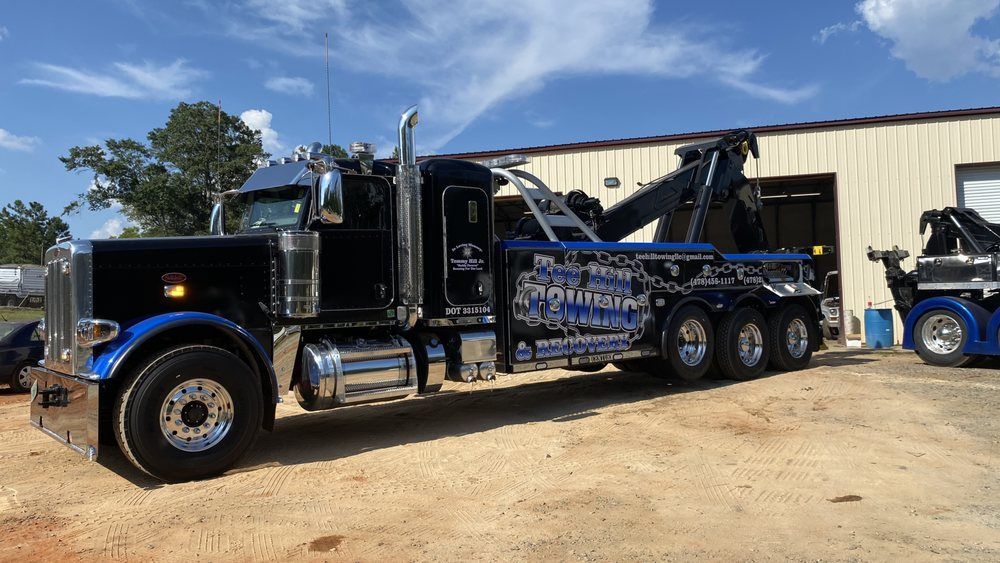A black and blue tow truck is parked in front of a building.
