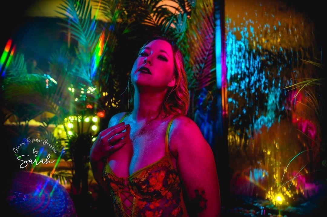 A woman in a floral dress is standing in front of a colorful wall.