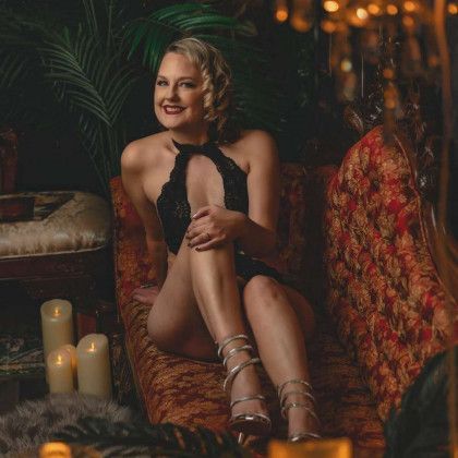 A woman in lingerie is sitting on a couch next to candles.