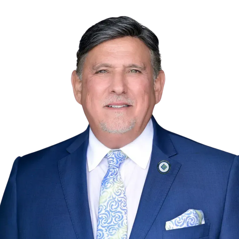 Man in blue suit, patterned tie, smiling, appears to be in a professional setting.