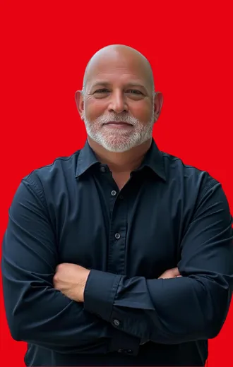 Man with crossed arms, wearing a black shirt, against a red background.