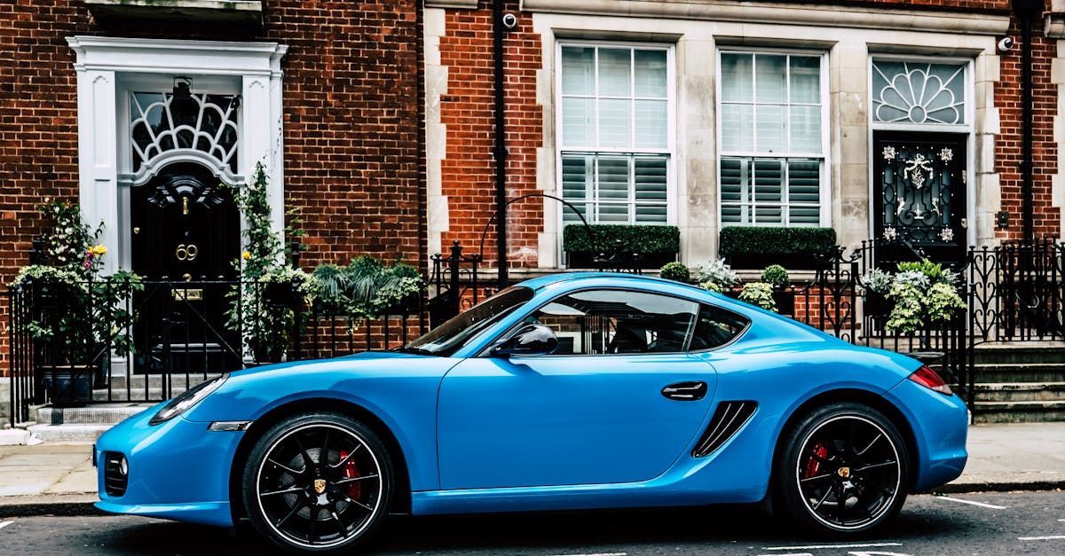 A blue sports car is parked on the side of the road in front of a brick building. | Eurotech German 