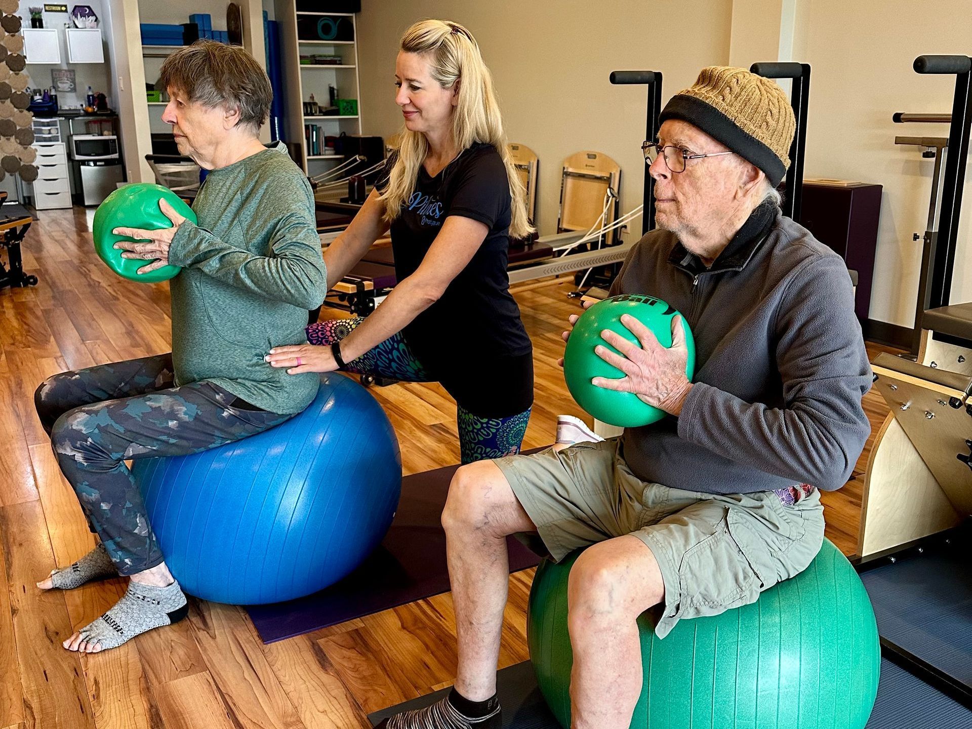 A group of people are sitting on exercise balls in a gym.