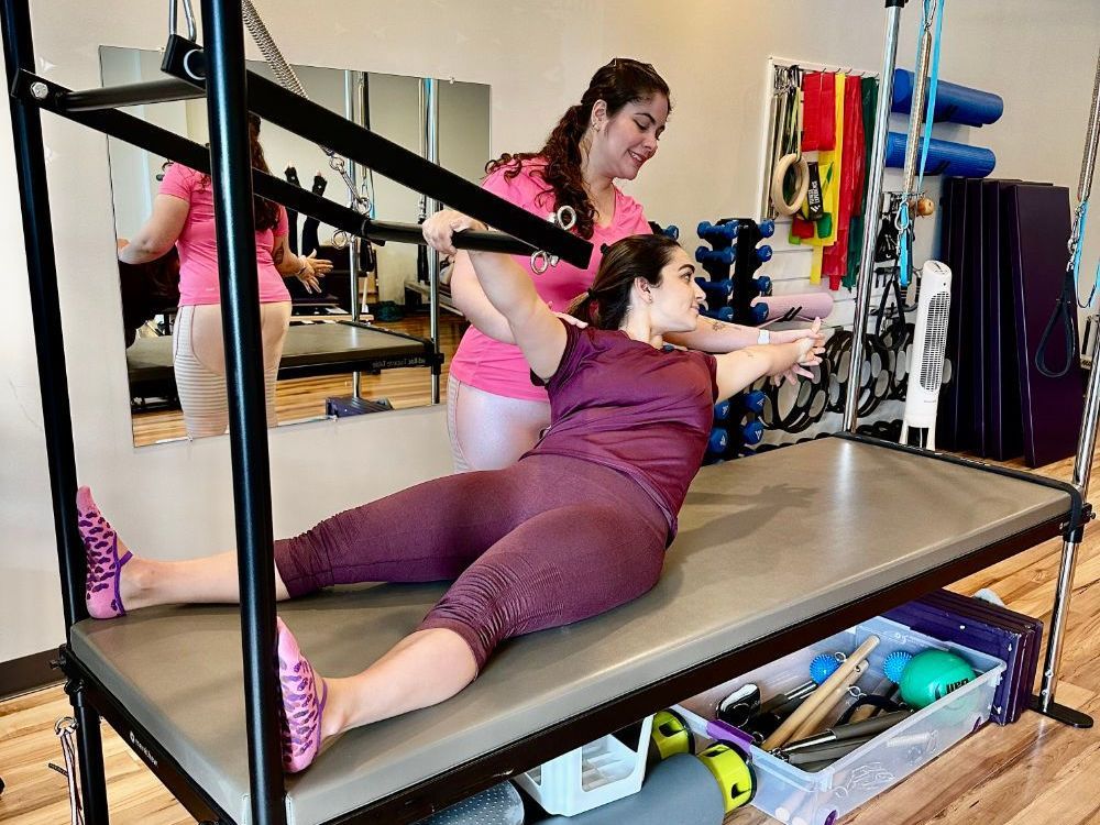 A woman is laying on a pilates machine in a gym.