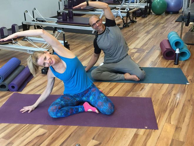 A man and a woman are doing yoga in a gym