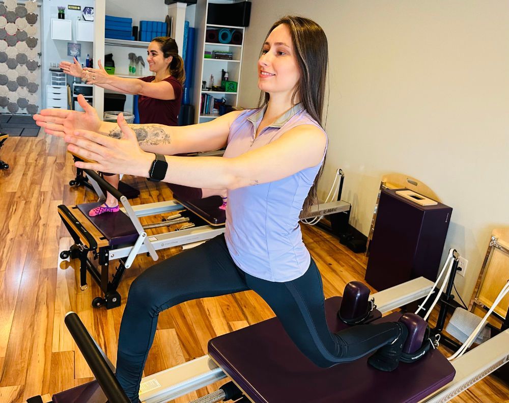 A woman is doing exercises on a pilates machine in a gym.