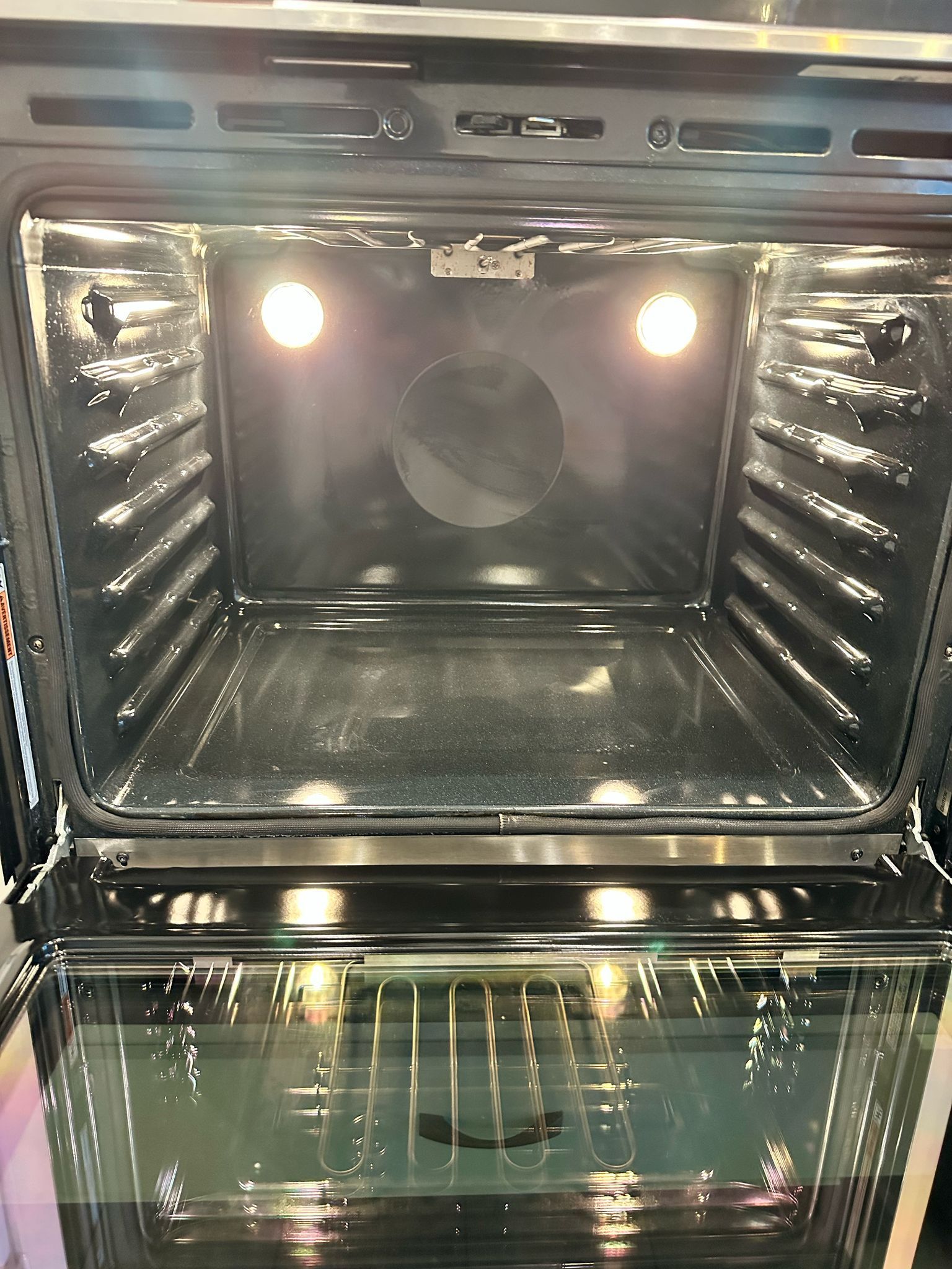 The inside of an oven with the door open and the lights on.