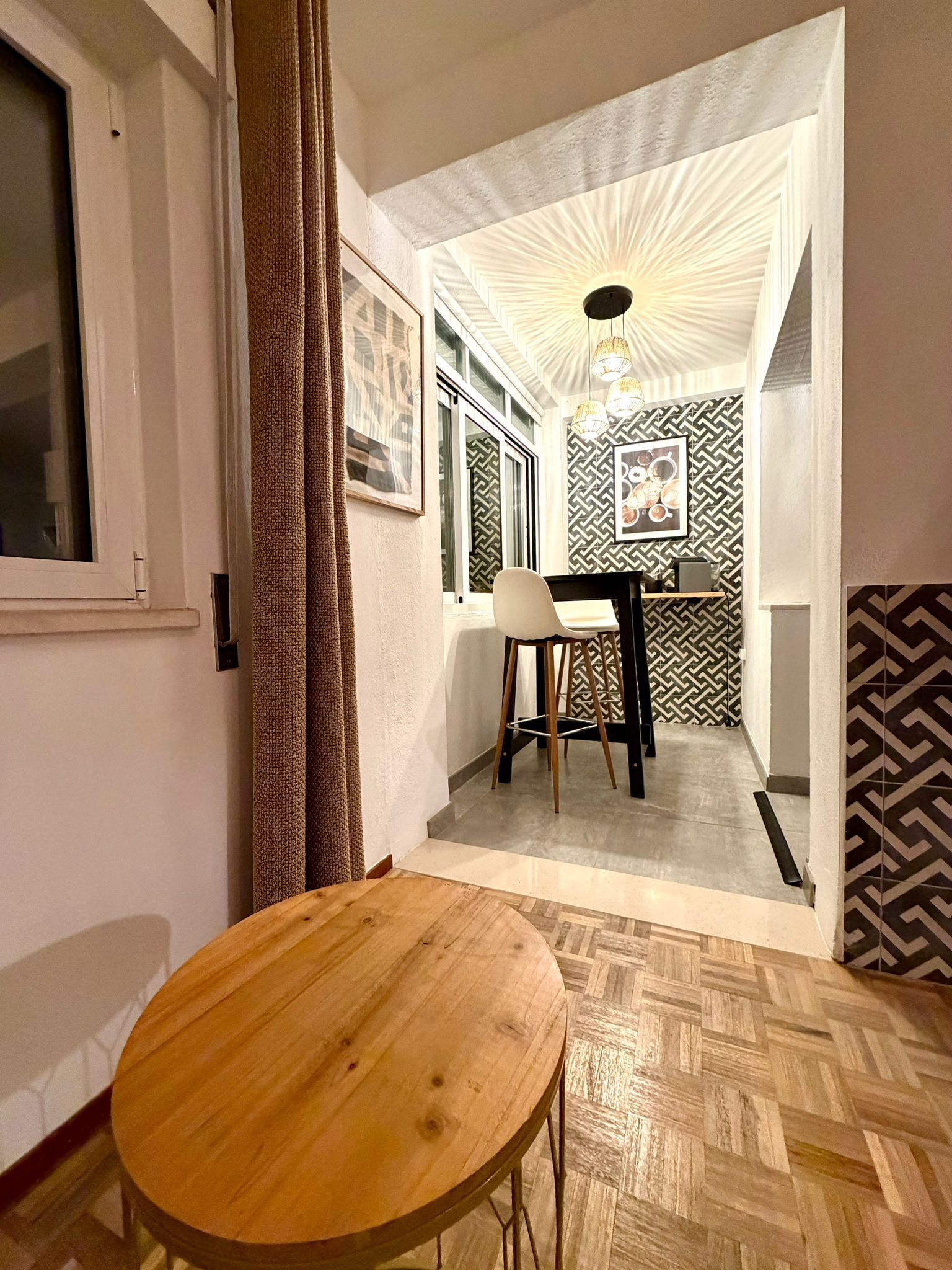 Smalle hal met eethoek en wasruimte. Zwart-wit interieur met kunstwerken, tafel en wasmachine.