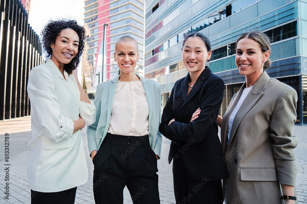 A group of women in business suits are posing for a picture in front of a building.