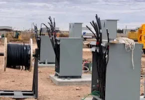 A bunch of electrical equipment is sitting on top of a dirt field.