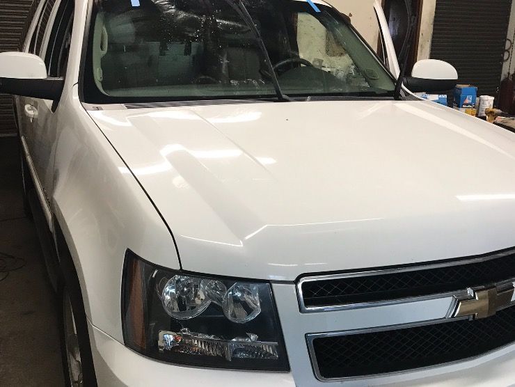 Front view of a white Chevrolet Tahoe SUV parked inside a workshop.