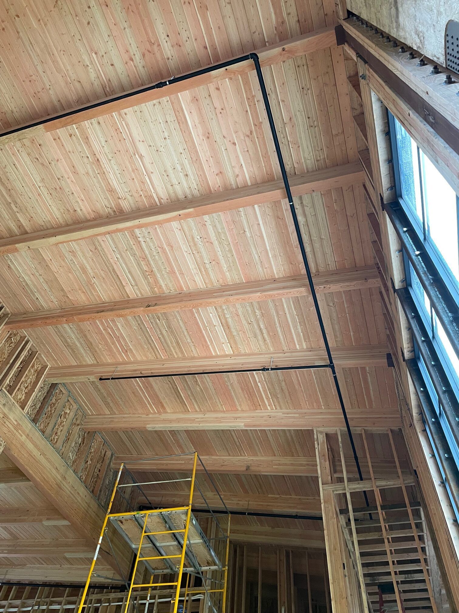 A large room with a wooden ceiling and stairs.