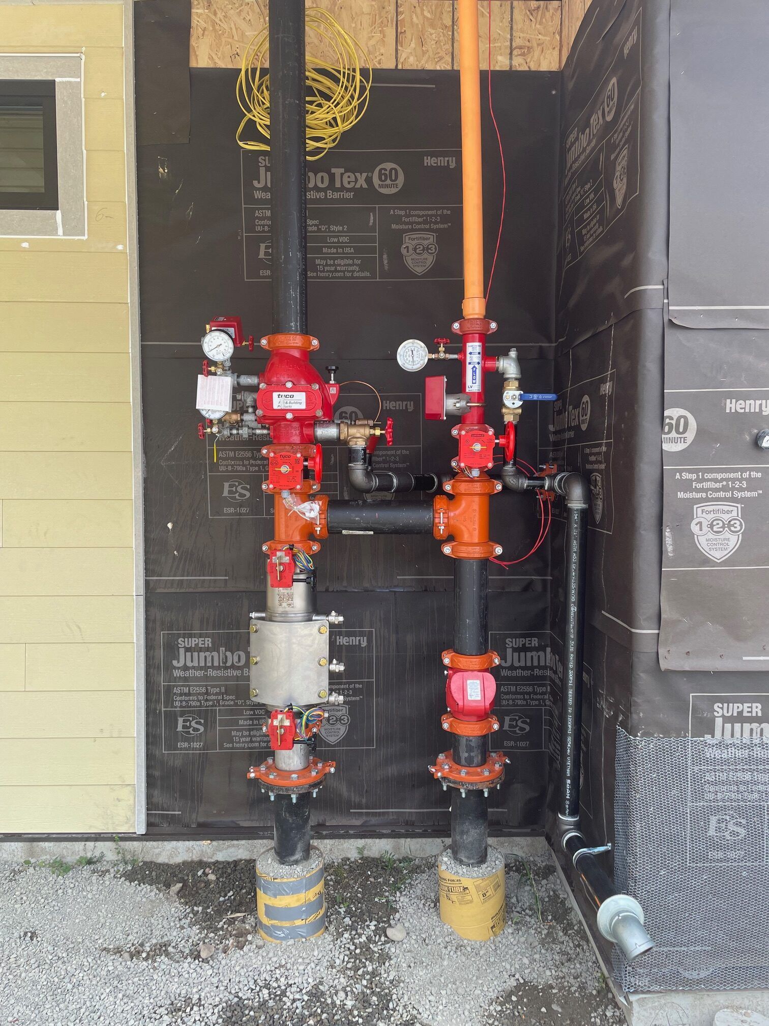 Two fire hydrants are sitting next to each other on the side of a building.