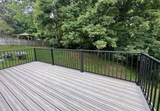 A deck with a black railing and trees in the background.