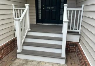 A porch with stairs leading up to the front door of a house.