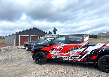 A red and black truck is parked in front of a garage.