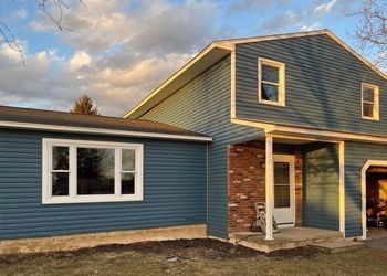 A house with a blue siding and white windows is for sale.