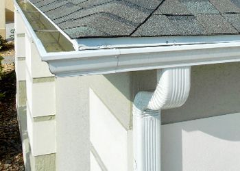 A white gutter is attached to the side of a house.