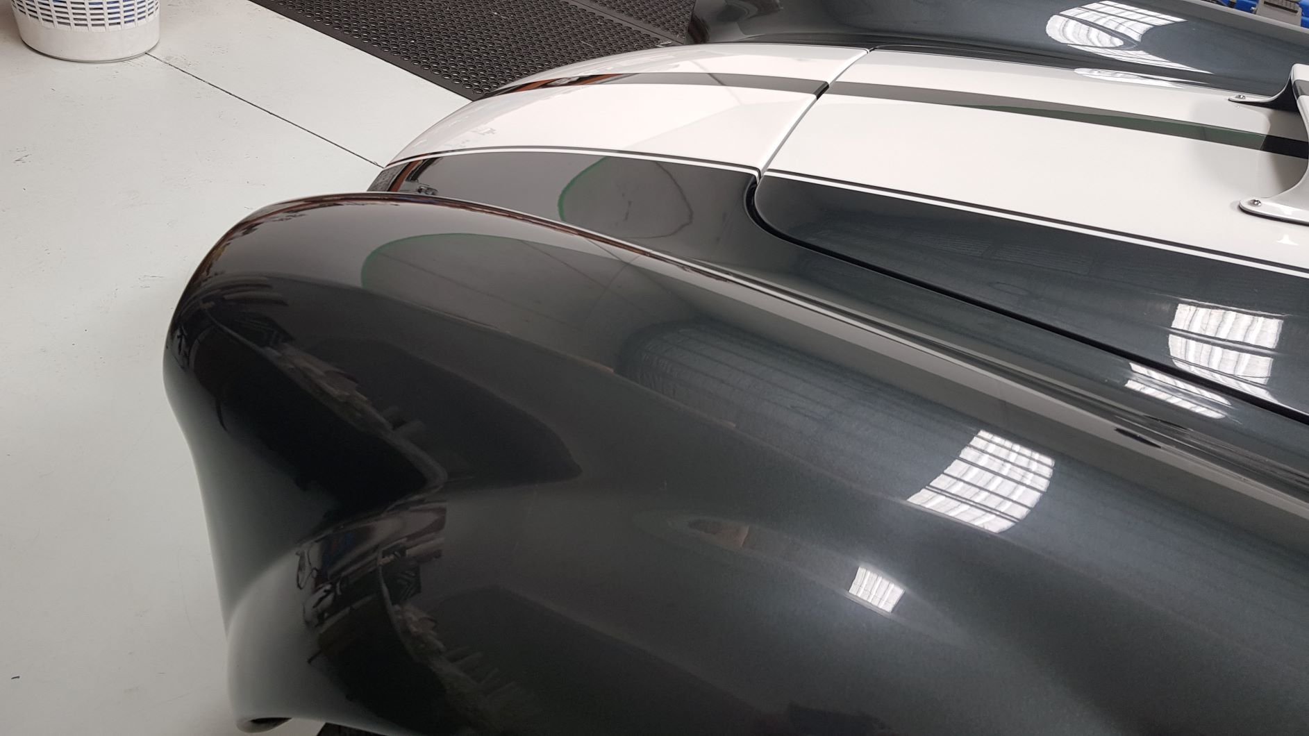 shows a close-up of the rear fender and part of the body of a classic car, Shelby Cobra