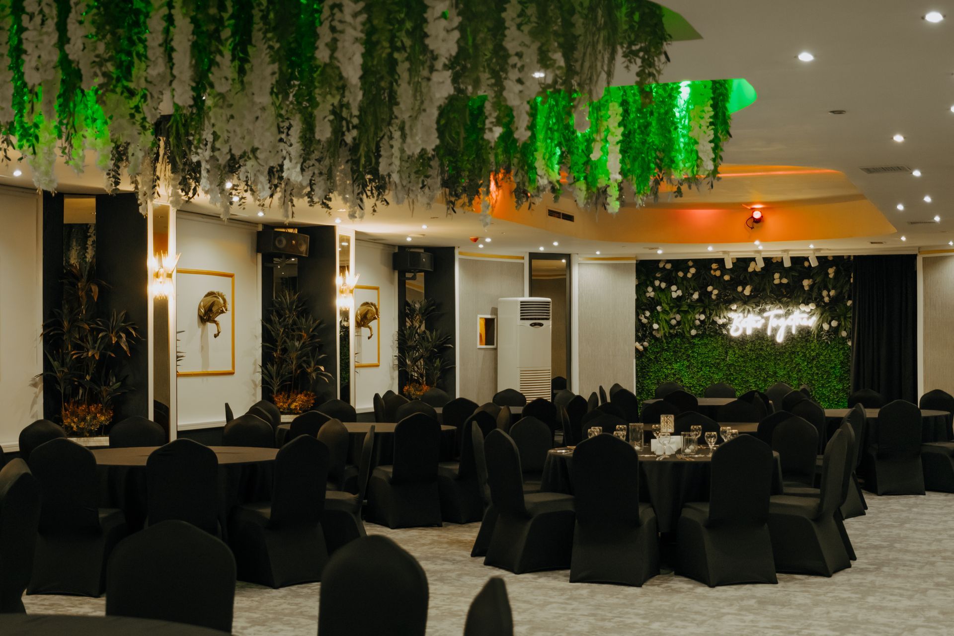 A large room with tables and chairs set up for a wedding reception.