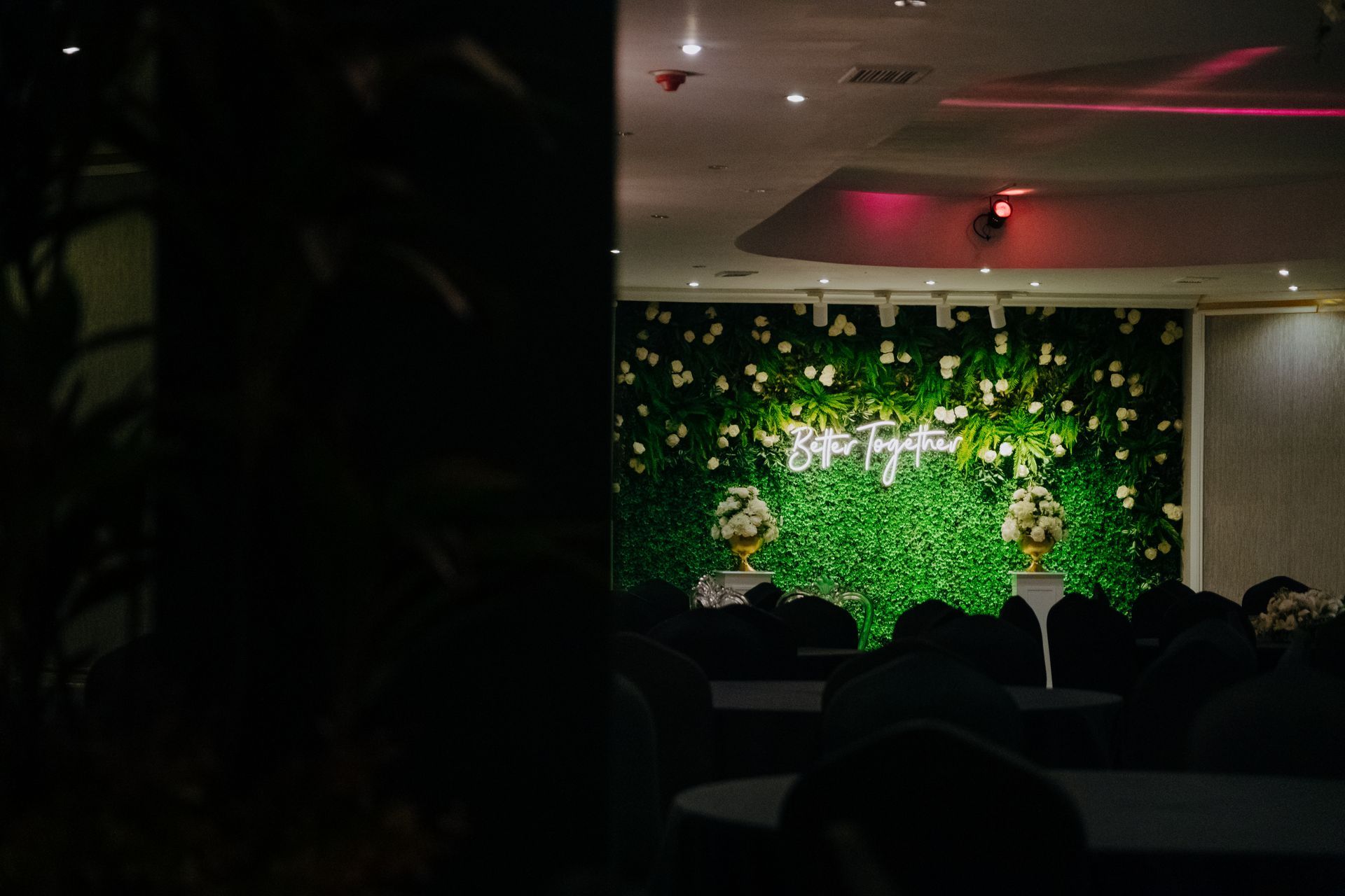 Masa ve sandalyelerin olduğu, üzerinde çiçekler olan yeşil bir duvar bulunan bir oda. | Aldino Hotel