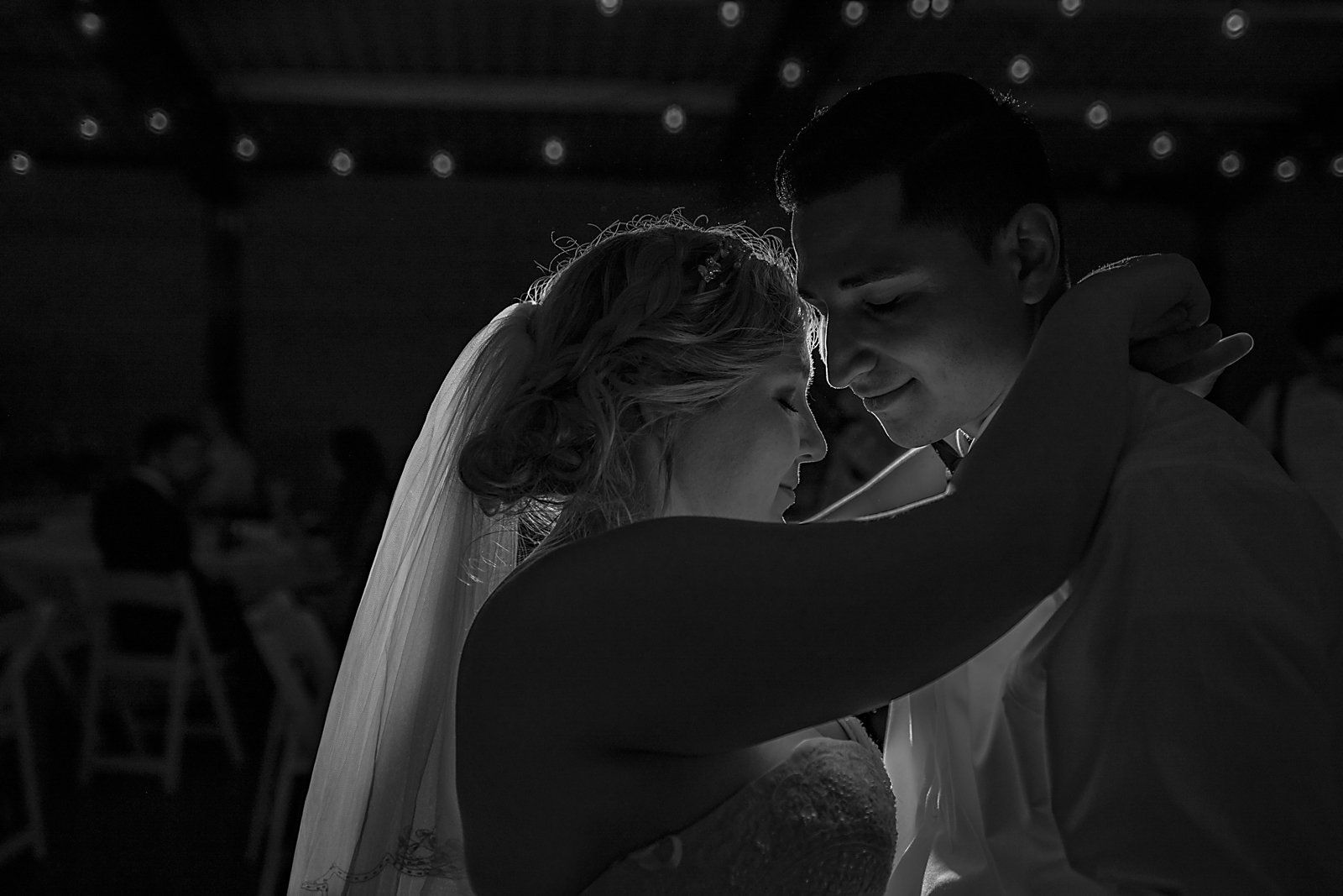 A black and white photo of a bride and groom dancing at their wedding reception.