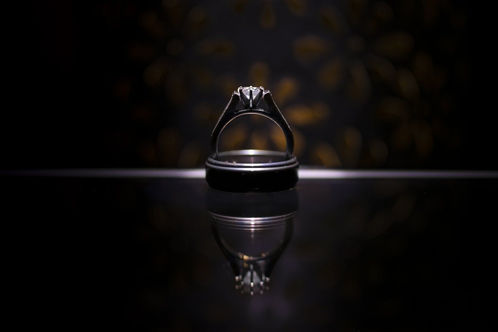 A close up of a wedding ring and engagement ring on a table.