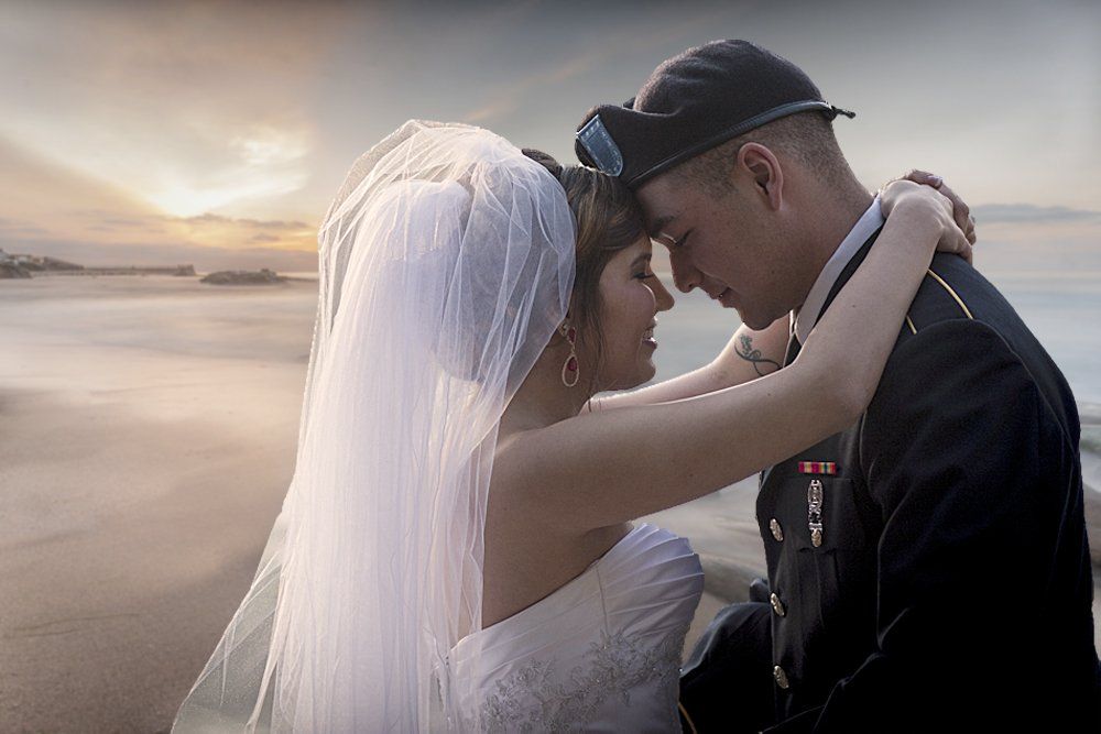 A bride and groom are standing next to each other on a beach.