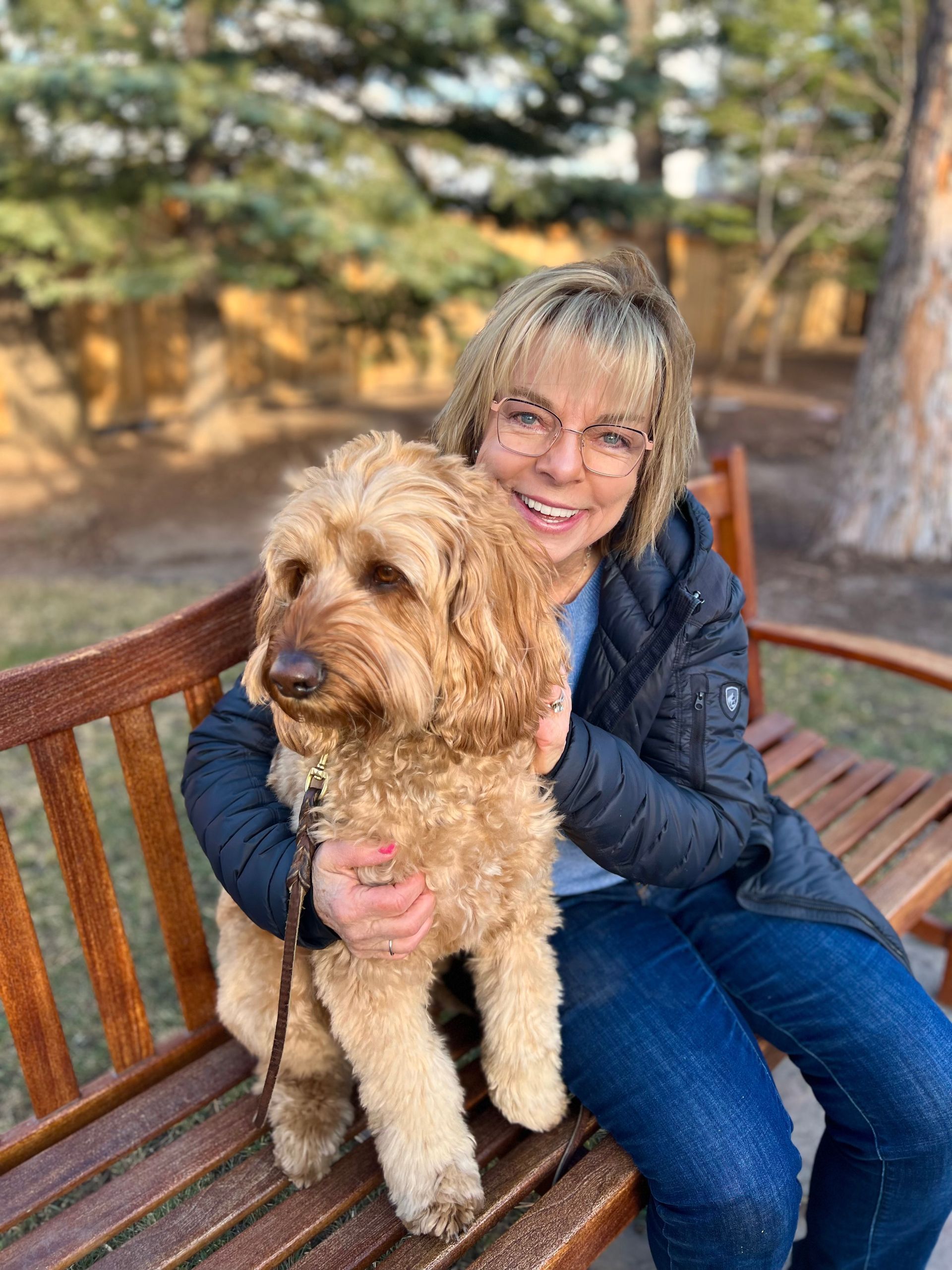 DeAnn Lauer sitting on a bench smiling with her cute dog, Winston