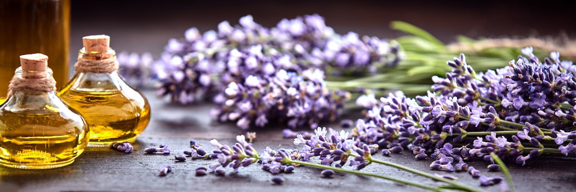 A bunch of lavender flowers and bottles of essential oil on a table.