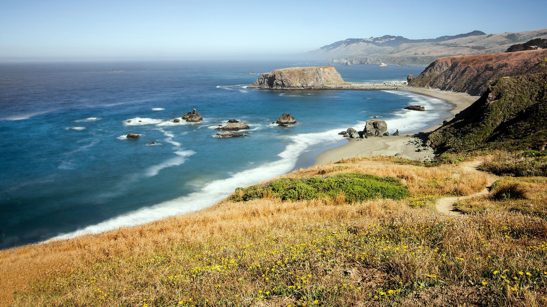 A view of a beach from a cliff overlooking the ocean