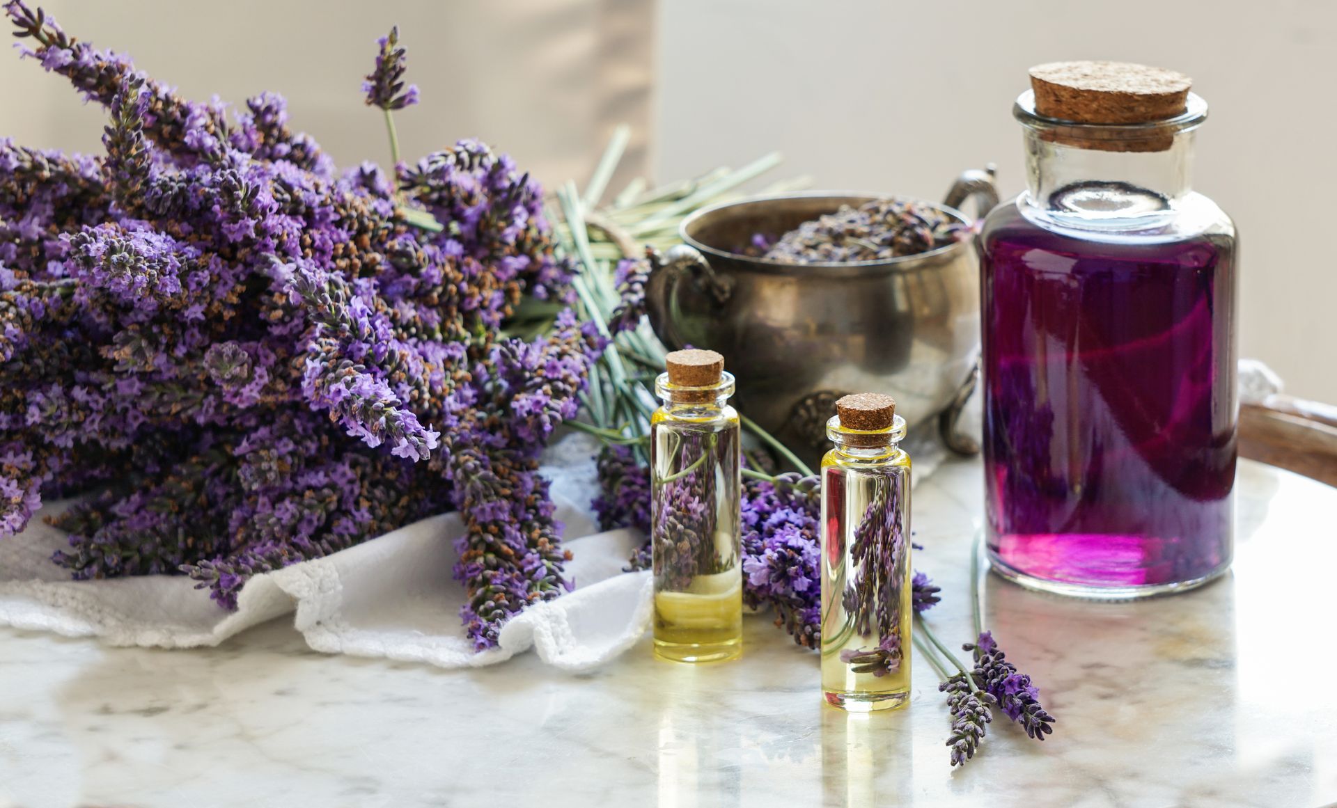 A bunch of lavender flowers and bottles of essential oil on a table.