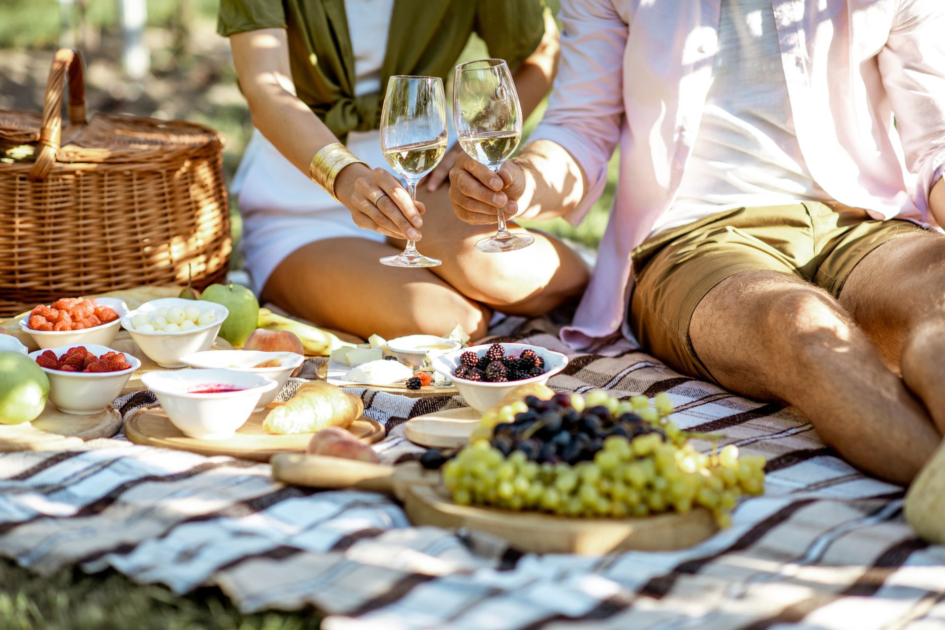 A couple is having a picnic in the park and drinking wine.