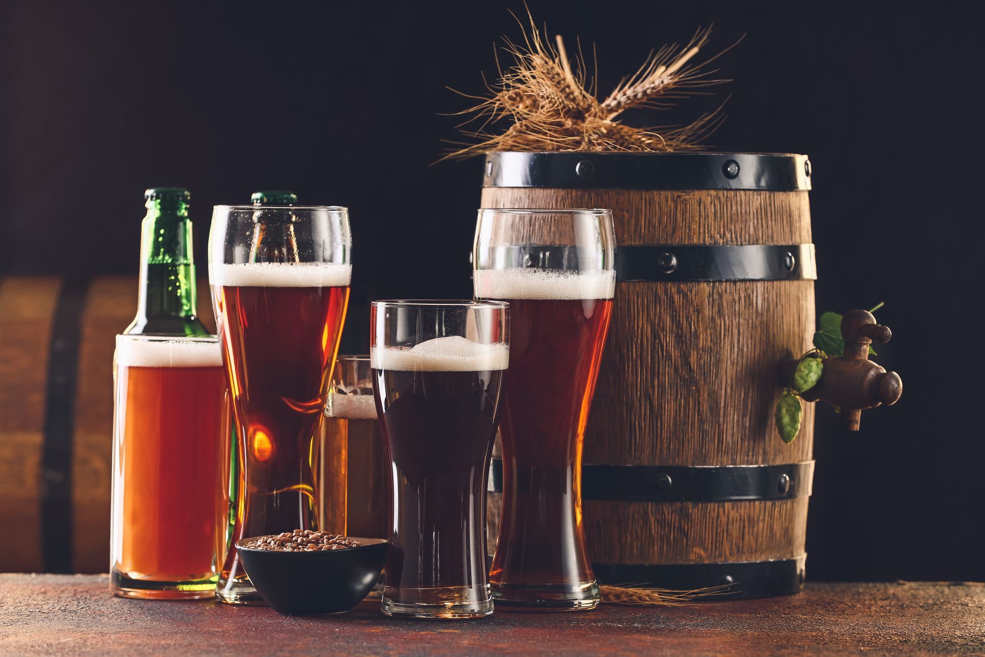 There are many different types of beer in glasses and bottles on the table.