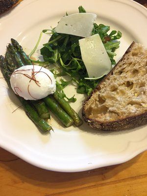 A white plate topped with asparagus , a poached egg , and a slice of bread.