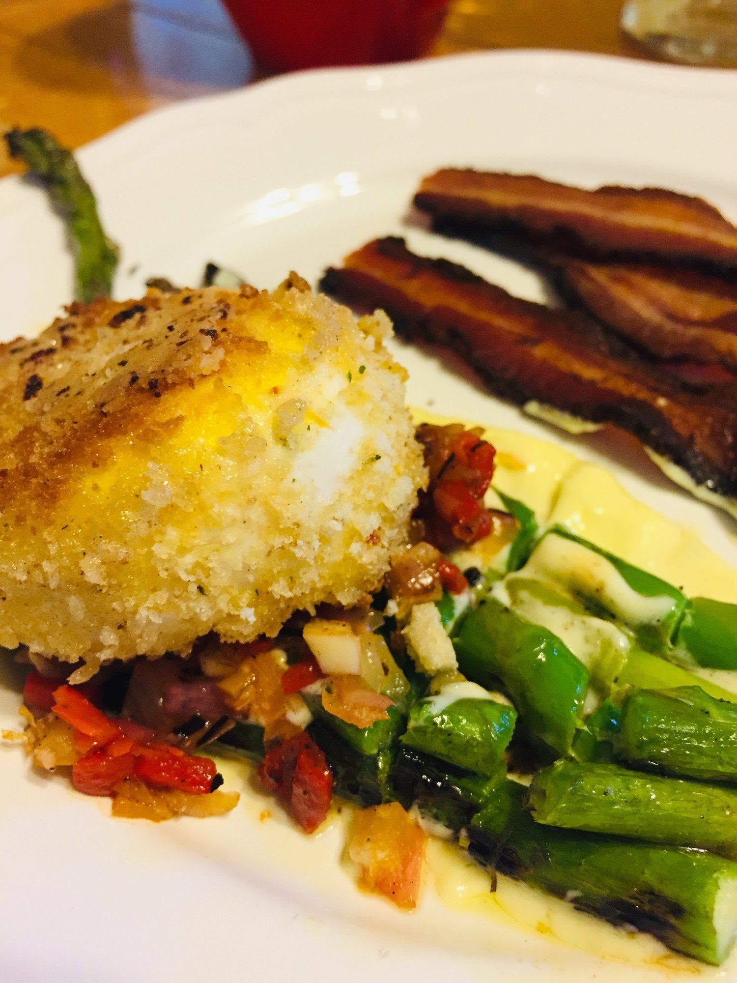 A close up of a plate of food with asparagus and bacon.