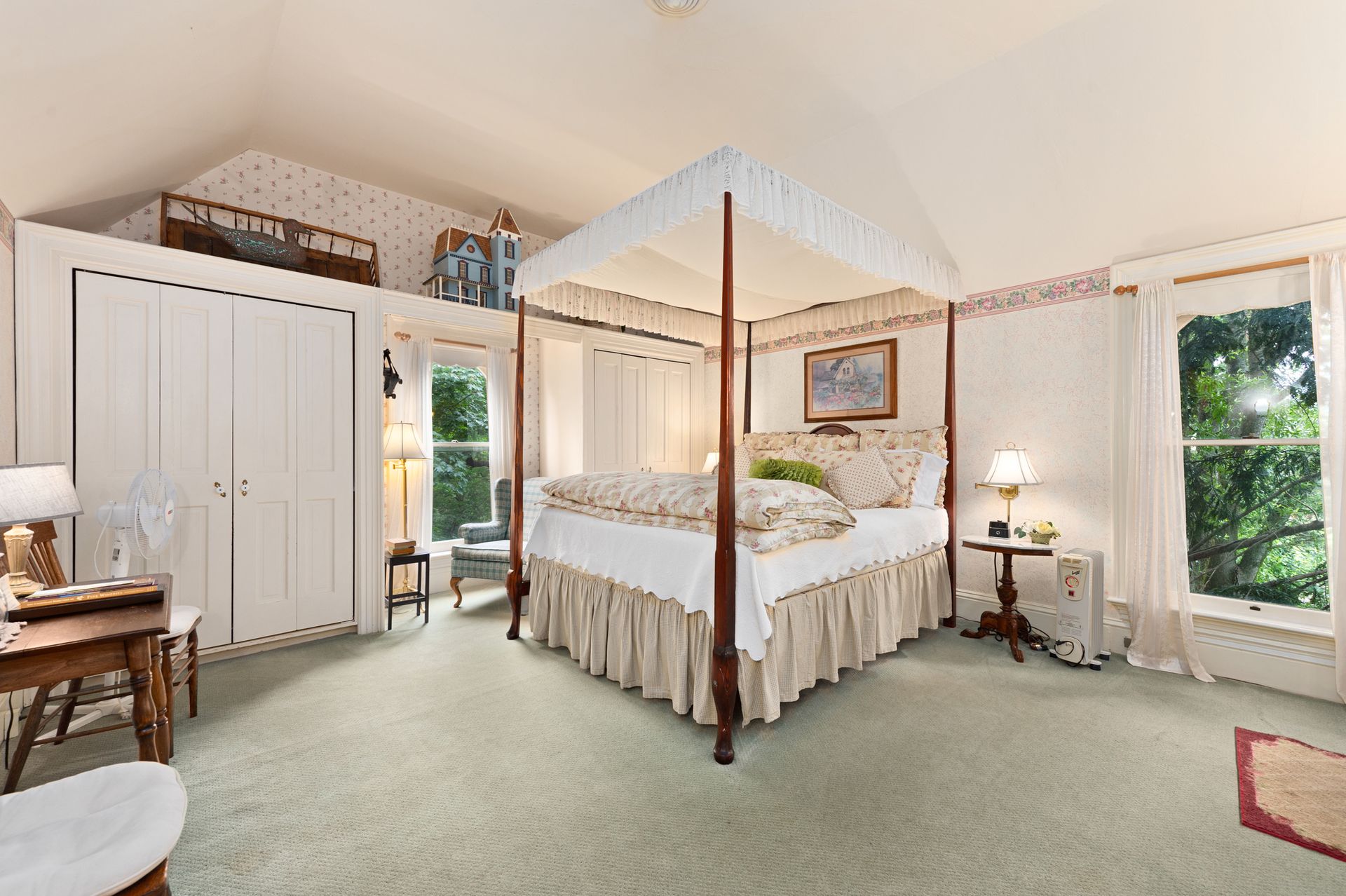 A bedroom with a four poster bed and a desk