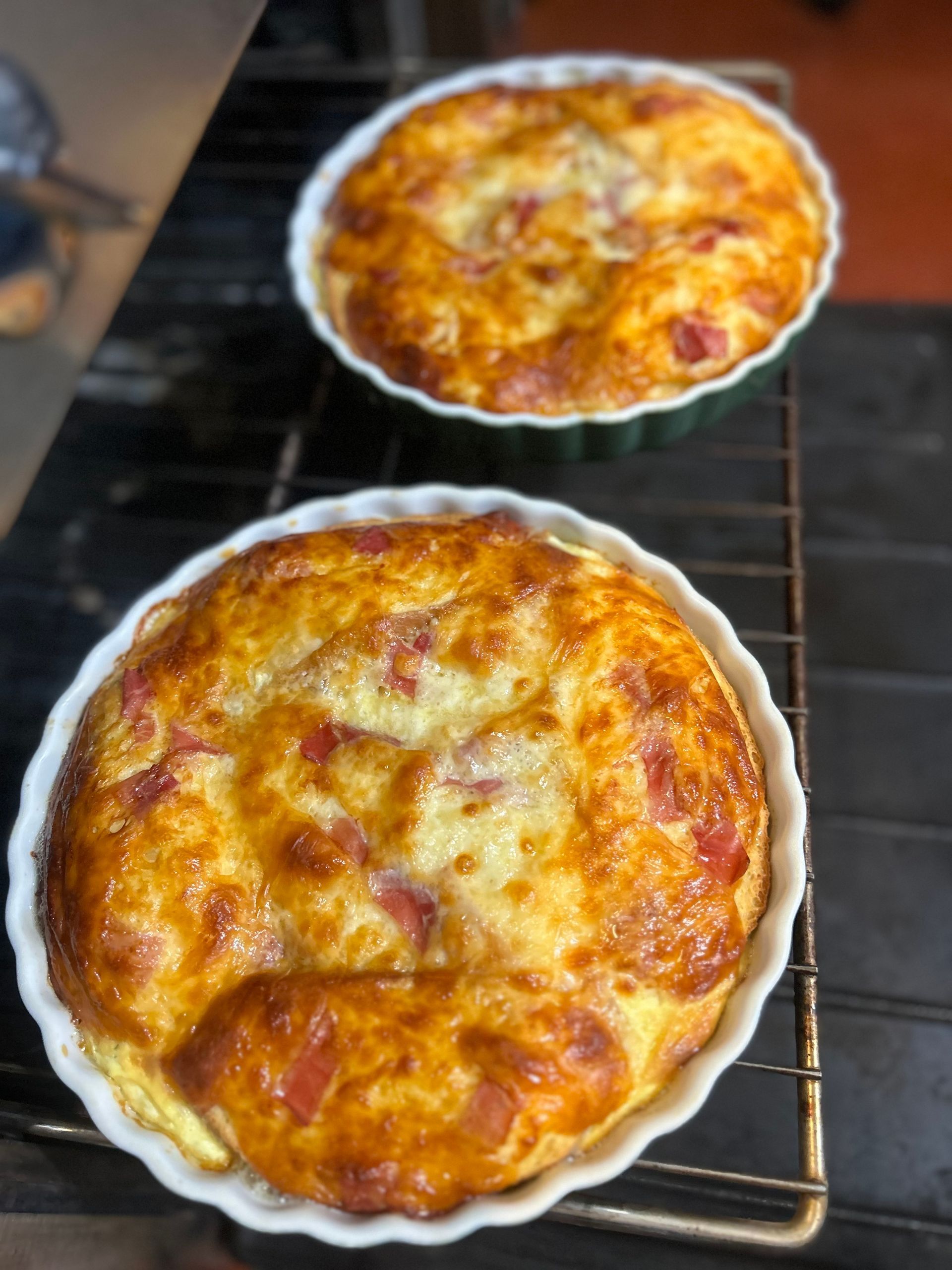 Two quiches are sitting on a wire rack on a stove.