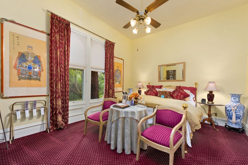 A bedroom with a table and chairs and a ceiling fan