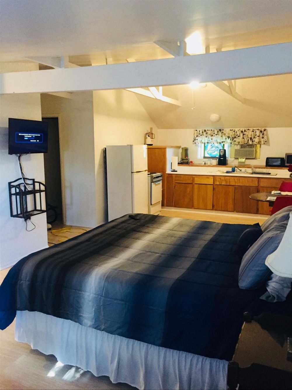 A bedroom with a large bed and a television on the wall.