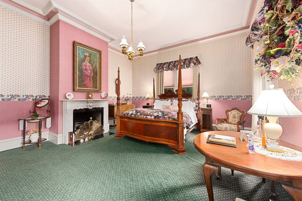 A bedroom with a four poster bed and a fireplace