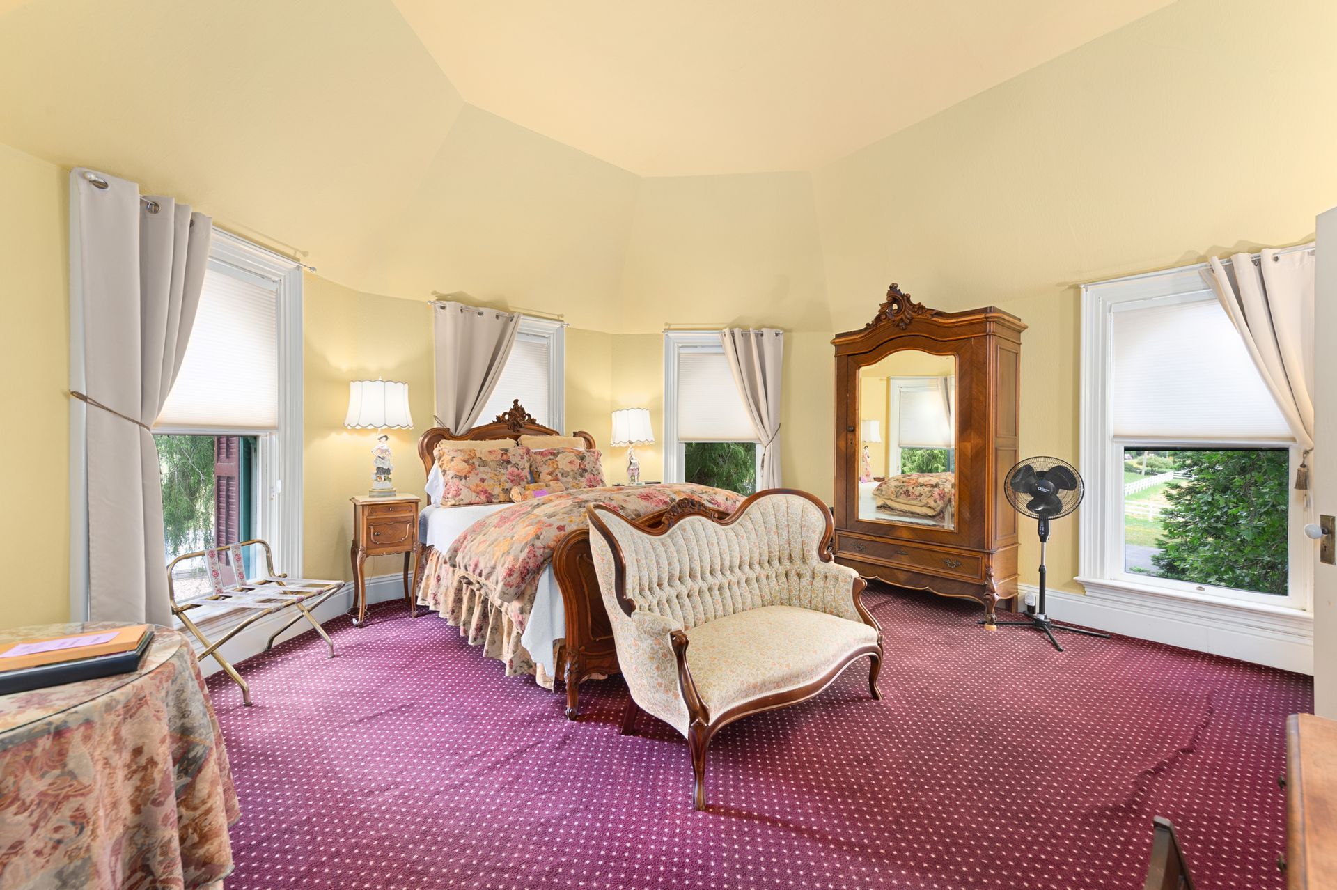 A bedroom with a bed , couch , mirror and window.