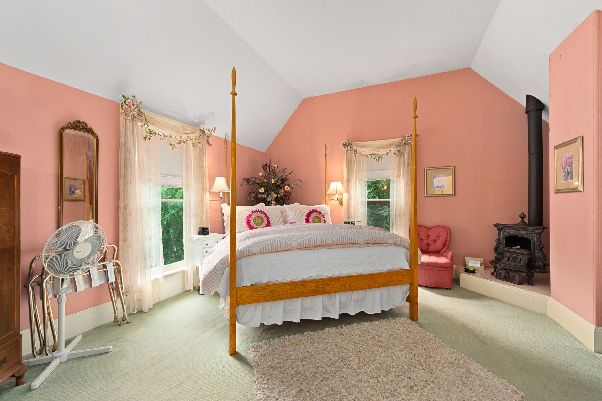 A bedroom with pink walls and a four poster bed