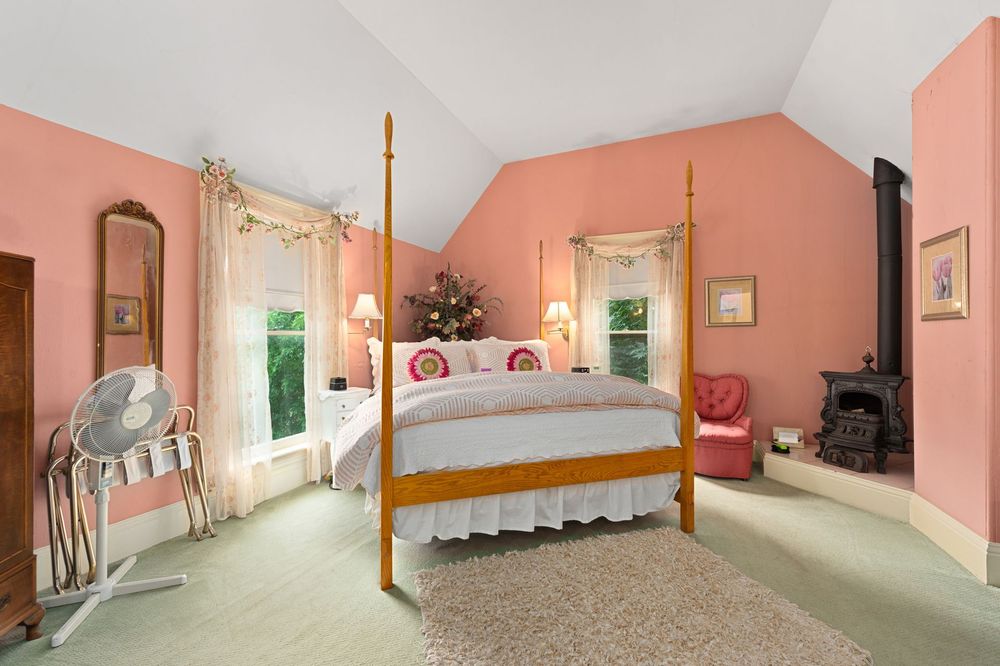 A bedroom with pink walls and a four poster bed