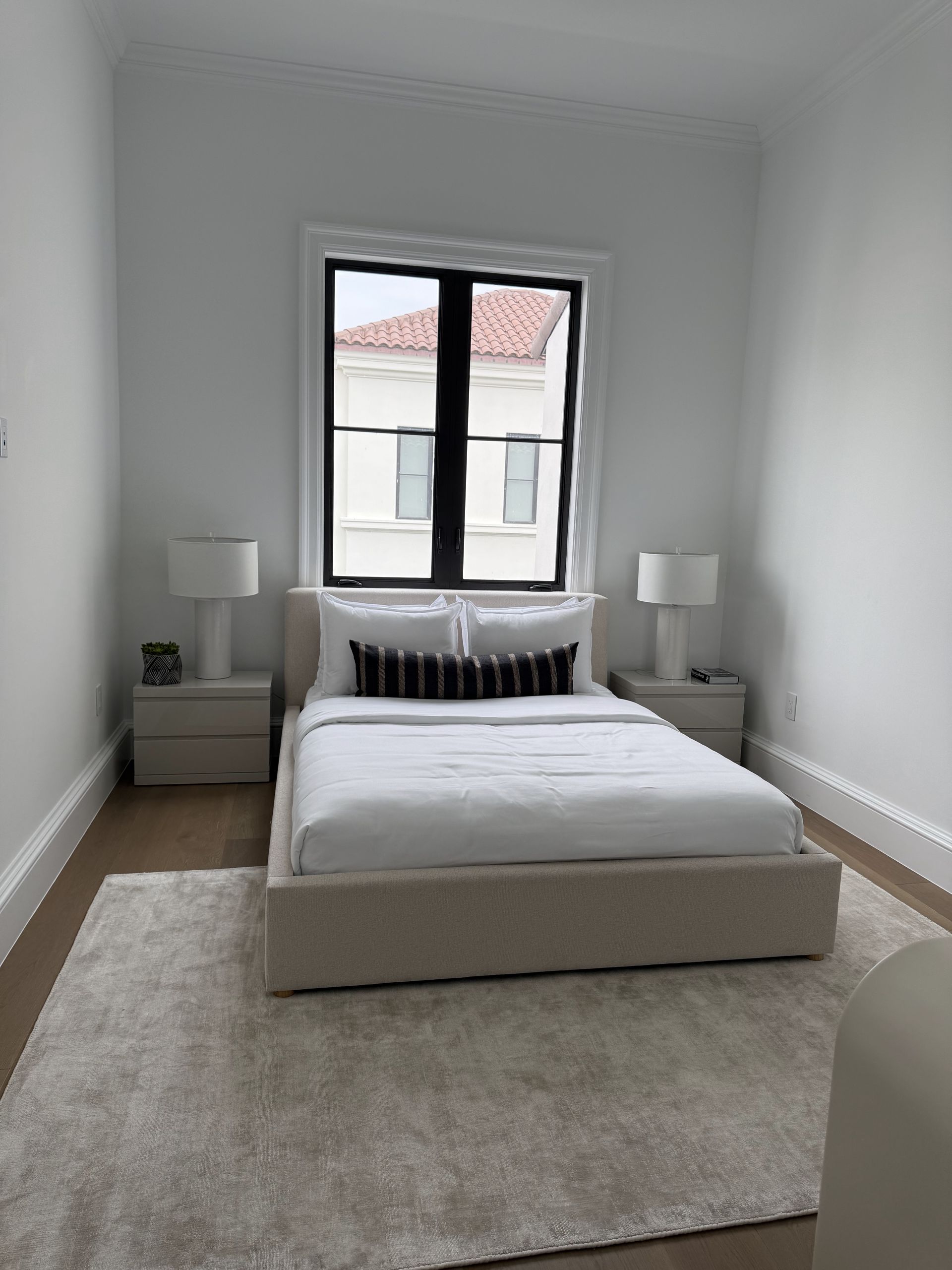 Bathroom with white countertops, black fixtures, leaf-patterned wall, large mirror.