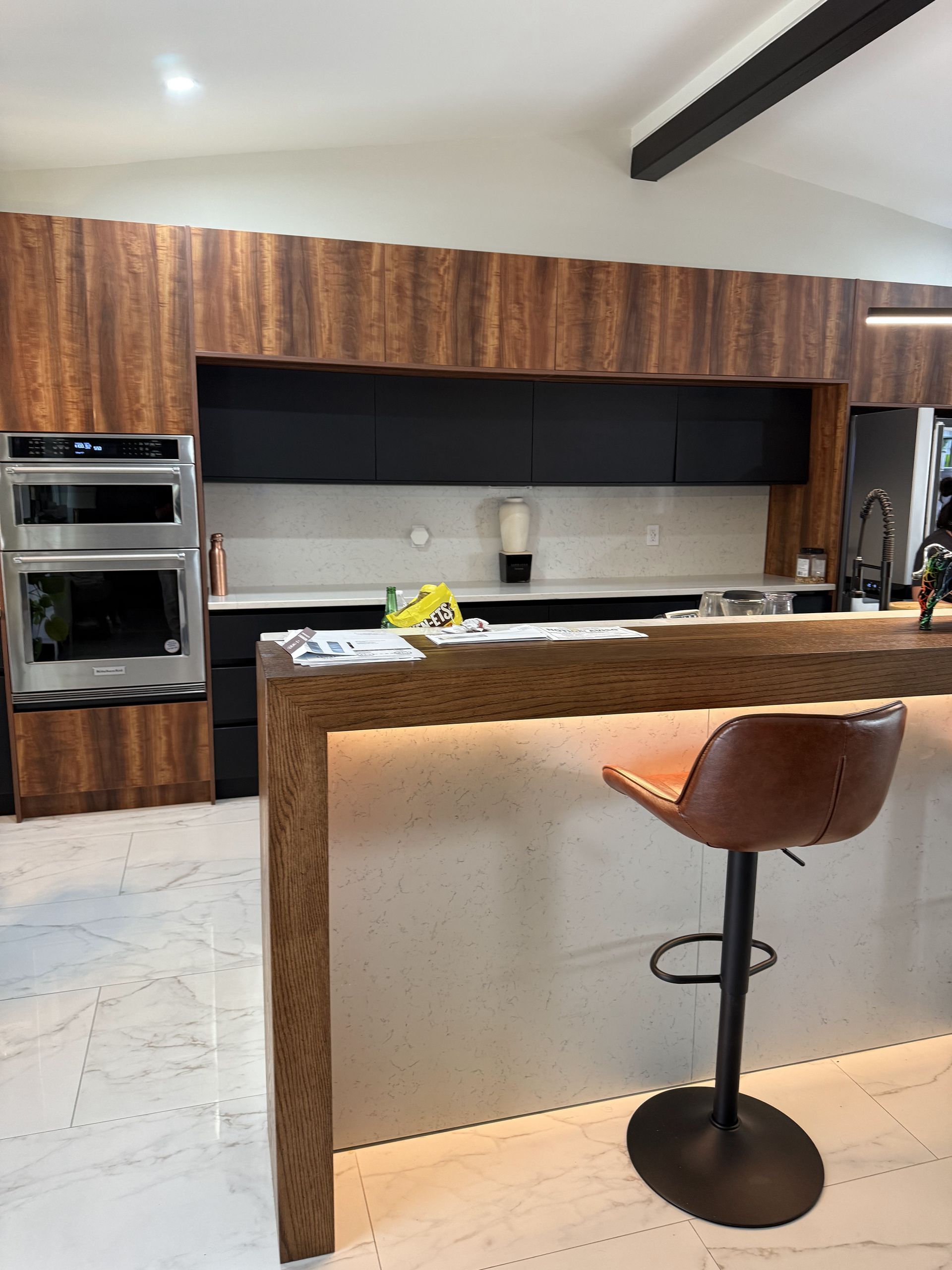 Outdoor seating area with gray sofa, wicker chairs, and artificial turf, against a stone wall.