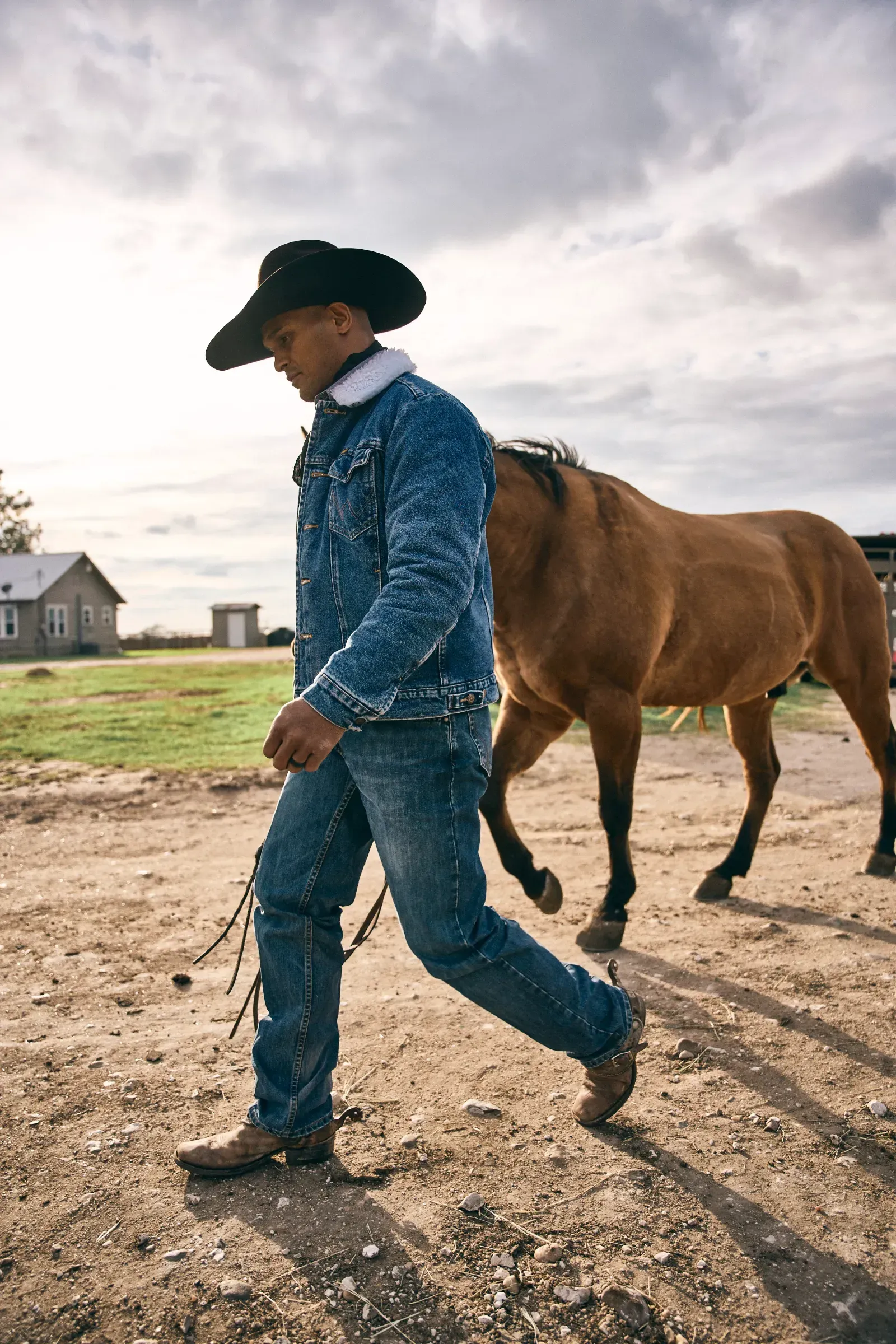 Texas cowboy standing at Thomas Cattle ranch with cattle in background.